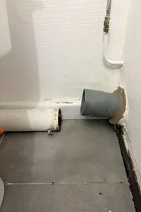 Conduite d’évacuation ouverte au ras du sol, après retrait des toilettes.